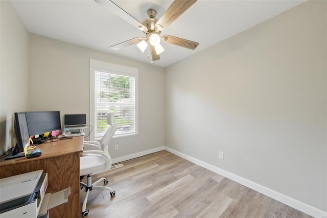 office featuring baseboards, a ceiling fan, and light wood-style flooring