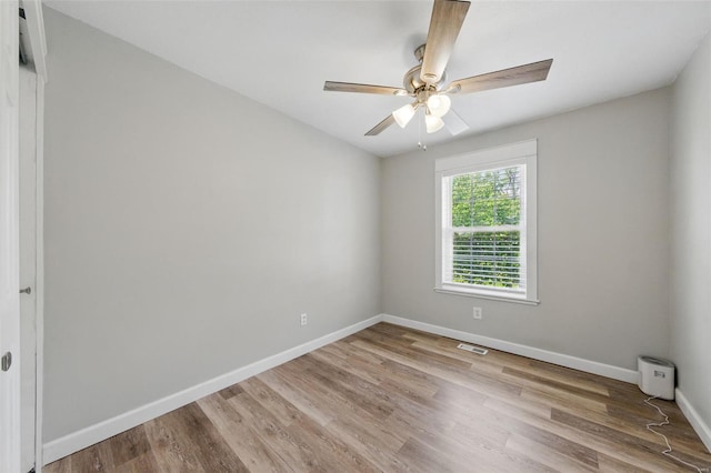empty room featuring ceiling fan, baseboards, visible vents, and wood finished floors