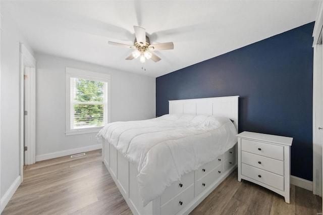 bedroom featuring light wood-style floors, baseboards, ceiling fan, and visible vents