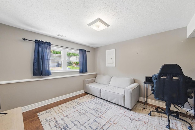office space featuring baseboards, a textured ceiling, wood finished floors, and visible vents