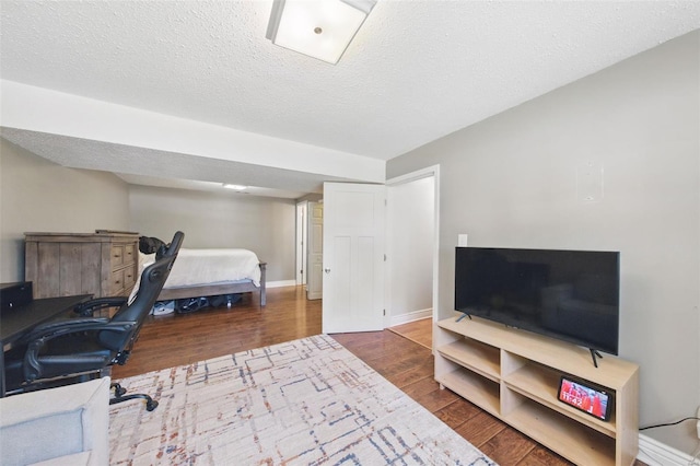 bedroom featuring baseboards, a textured ceiling, and wood finished floors