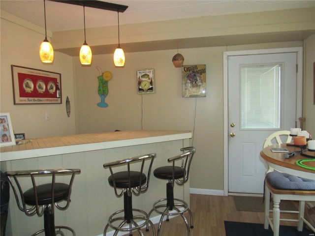 bar with hanging light fixtures and wood finished floors