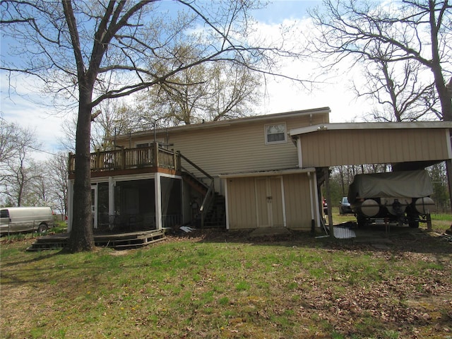 rear view of property featuring a lawn, a carport, a wooden deck, and stairs