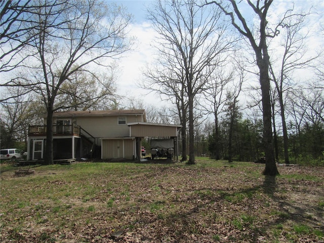 view of yard with a carport, a wooden deck, and stairway