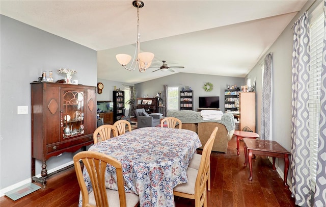 dining area with ceiling fan with notable chandelier, dark wood-type flooring, visible vents, vaulted ceiling, and baseboards
