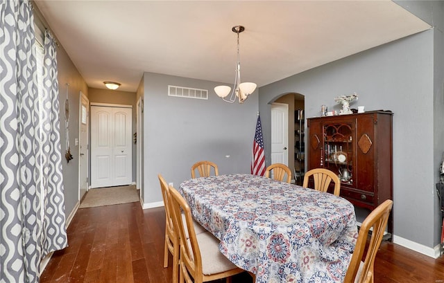 dining room featuring arched walkways, baseboards, visible vents, and dark wood-style floors