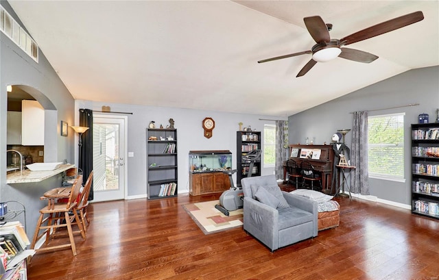 living room featuring vaulted ceiling, a ceiling fan, visible vents, arched walkways, and wood-type flooring