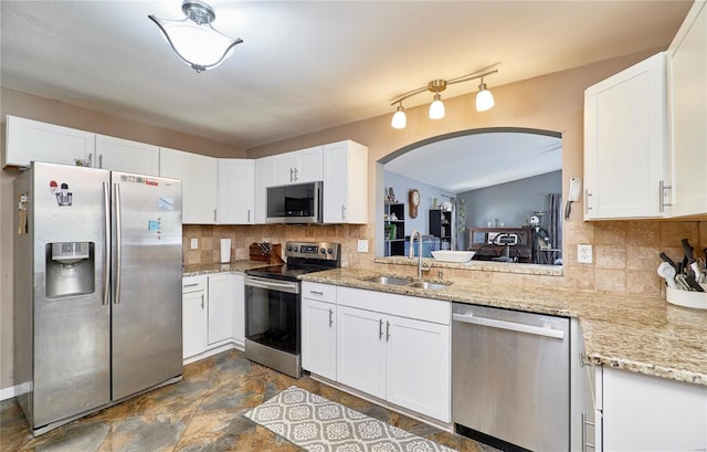kitchen with a sink, decorative backsplash, appliances with stainless steel finishes, and arched walkways