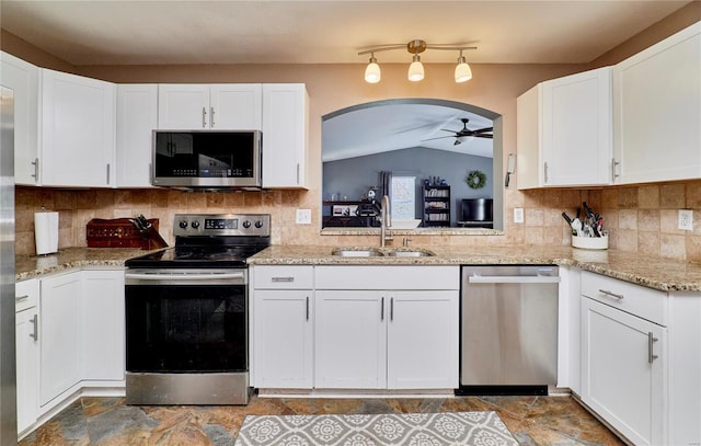 kitchen featuring tasteful backsplash, a sink, appliances with stainless steel finishes, a ceiling fan, and lofted ceiling