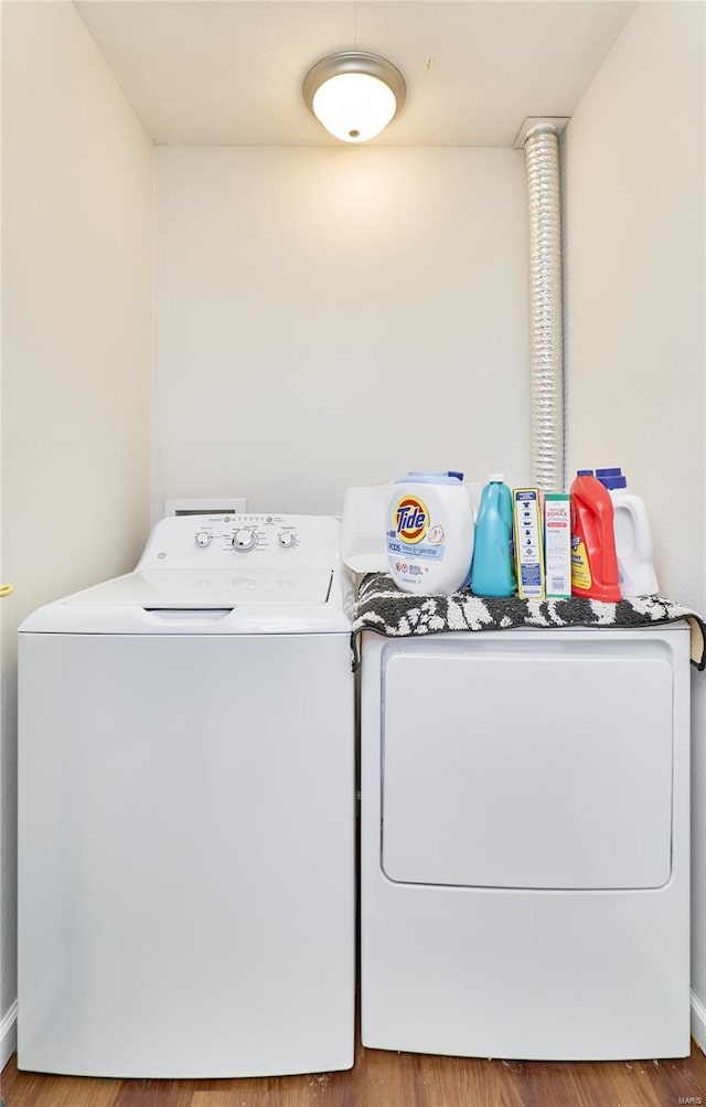 laundry room featuring washing machine and clothes dryer, wood finished floors, laundry area, and baseboards