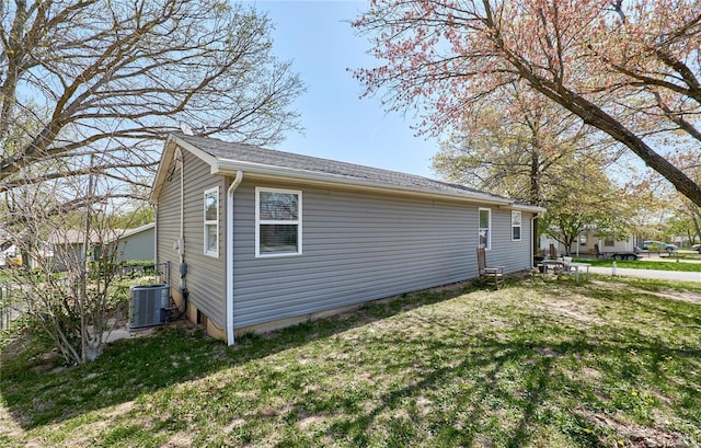 view of side of property featuring central air condition unit and a lawn