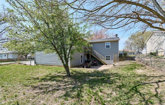 back of house featuring a yard, stairway, and a fenced backyard