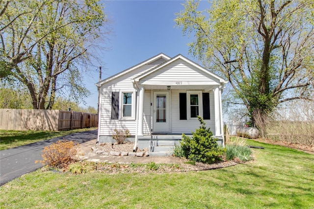 bungalow-style home with a porch, a front yard, and fence