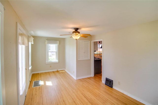empty room with baseboards, a ceiling fan, visible vents, and light wood-style flooring