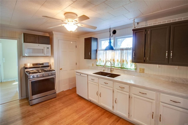 kitchen featuring white appliances, a sink, light wood-style floors, and crown molding