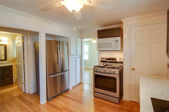 kitchen with light wood-style floors, ornamental molding, a ceiling fan, and stainless steel appliances