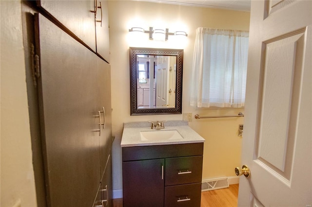 bathroom with baseboards, wood finished floors, visible vents, and vanity