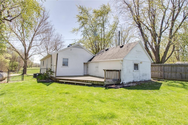 rear view of house featuring a wooden deck, a shingled roof, a fenced backyard, and a gate