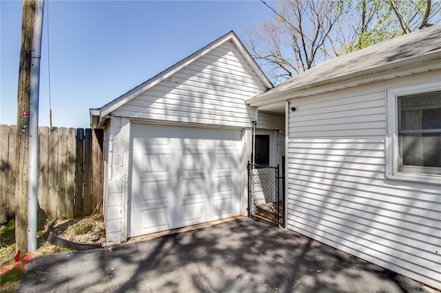 detached garage featuring a gate, driveway, and fence
