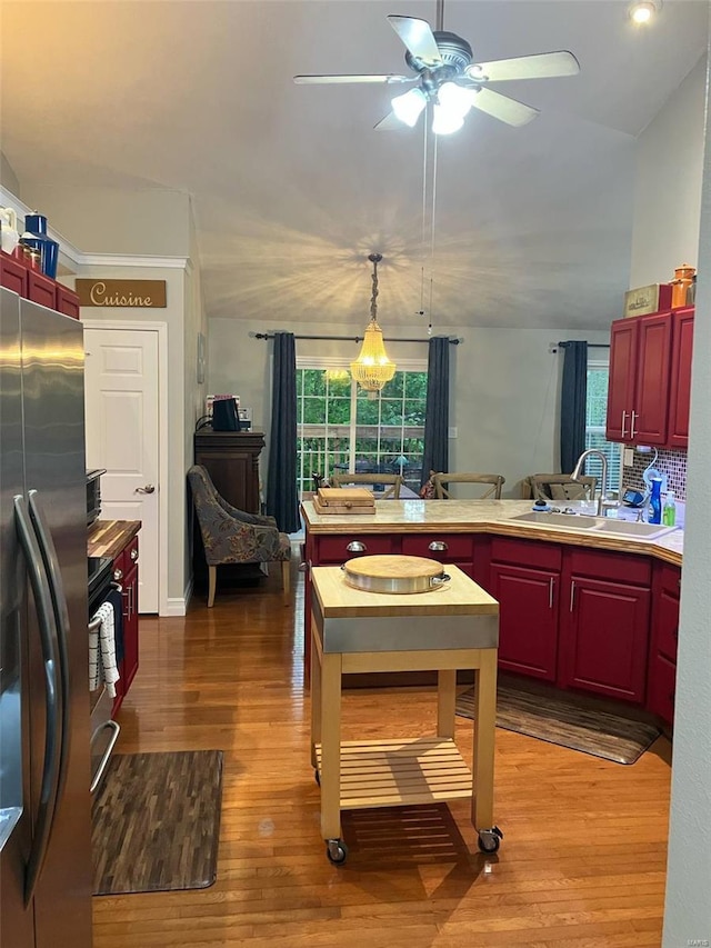 kitchen with freestanding refrigerator, a ceiling fan, a peninsula, a sink, and a wealth of natural light