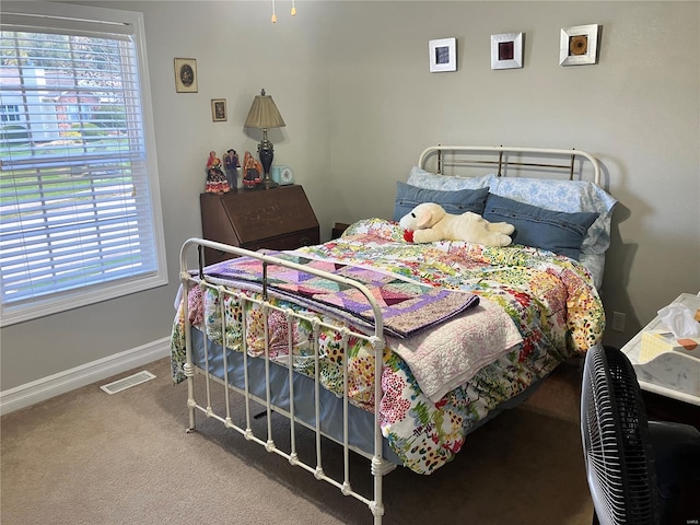 carpeted bedroom featuring baseboards, multiple windows, and visible vents