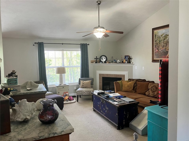 living area featuring a tiled fireplace, a ceiling fan, carpet flooring, and vaulted ceiling