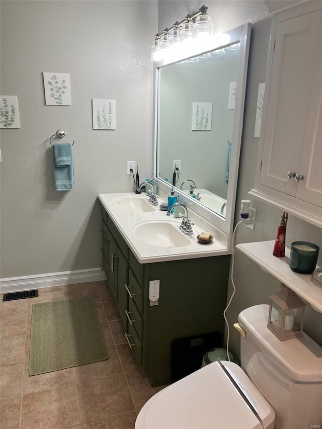 bathroom with toilet, a sink, and tile patterned flooring