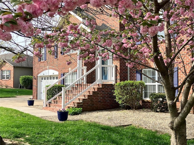view of front of property featuring a garage, a front yard, and brick siding