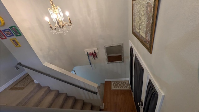 stairway with baseboards, an inviting chandelier, and wood finished floors
