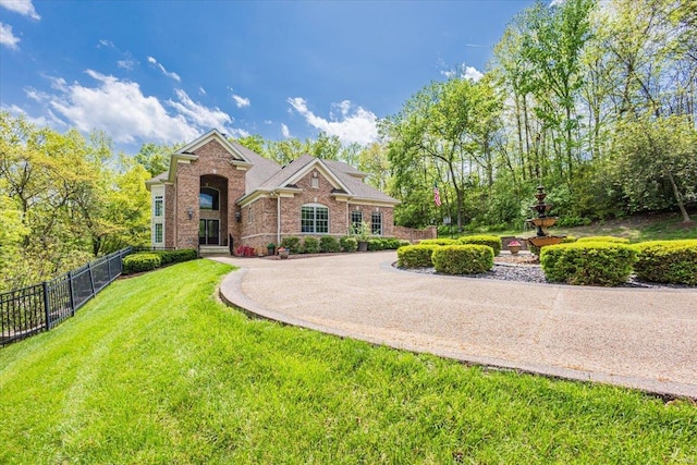 view of front facade with brick siding, a front lawn, and fence