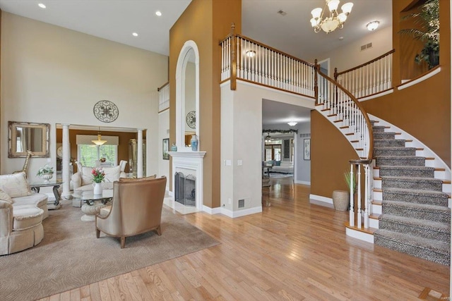 living area featuring visible vents, a towering ceiling, stairs, wood finished floors, and recessed lighting