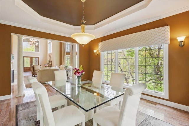 dining room featuring hardwood / wood-style floors, baseboards, a healthy amount of sunlight, and a tray ceiling