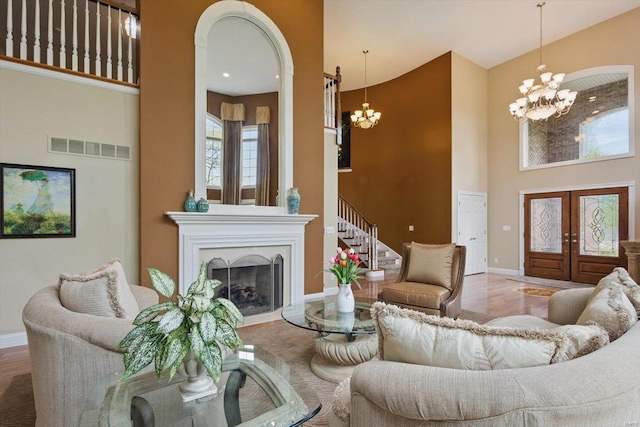 living room with an inviting chandelier, baseboards, a high ceiling, and visible vents