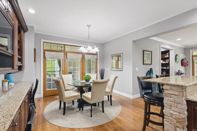dining space with crown molding, baseboards, an inviting chandelier, and light wood-style flooring