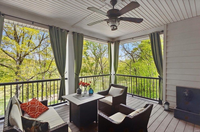 sunroom featuring a deck, a ceiling fan, wood ceiling, and hardwood / wood-style floors