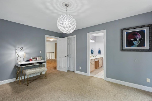 bedroom with baseboards, light carpet, ensuite bath, and a chandelier