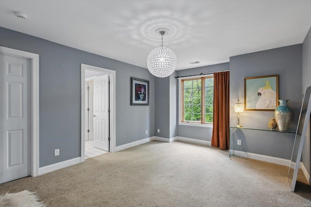 unfurnished bedroom with an inviting chandelier, carpet floors, baseboards, and visible vents