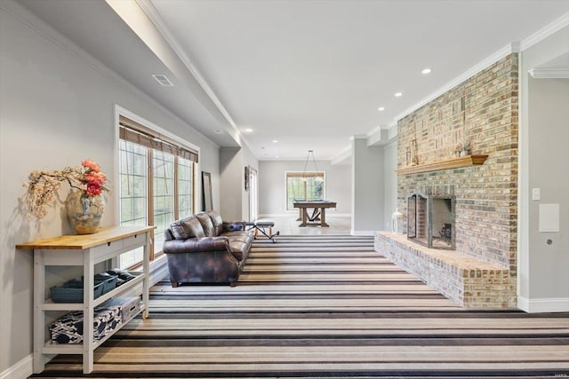 living area featuring baseboards, recessed lighting, a brick fireplace, and crown molding