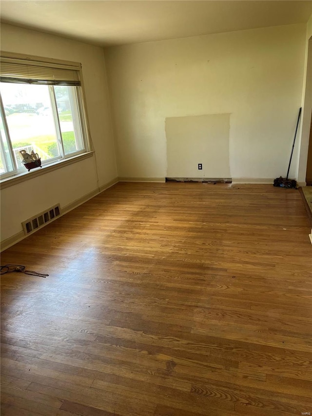 unfurnished room with wood finished floors, visible vents, and baseboards