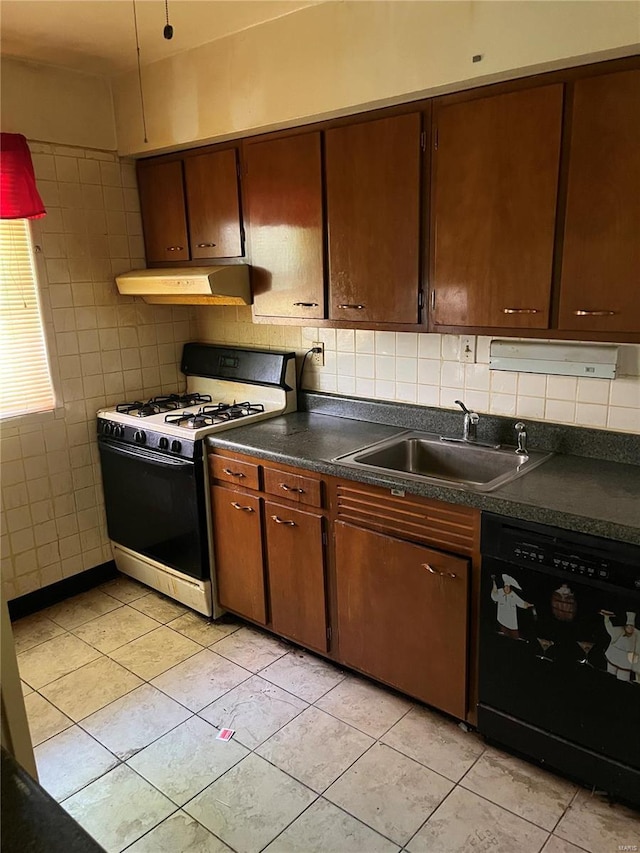 kitchen featuring range with gas stovetop, dark countertops, a sink, dishwasher, and under cabinet range hood