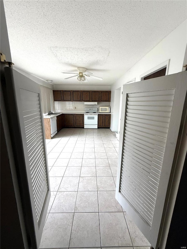 kitchen featuring a ceiling fan, a textured ceiling, white appliances, light tile patterned floors, and light countertops