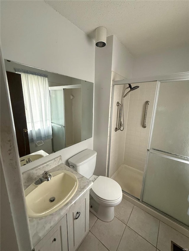 full bathroom featuring tile patterned floors, toilet, vanity, a textured ceiling, and a stall shower