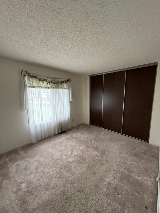 unfurnished bedroom featuring carpet, a textured ceiling, and a closet