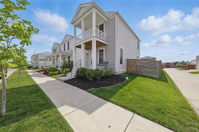 view of front of home featuring a residential view, fence, a front lawn, and a balcony