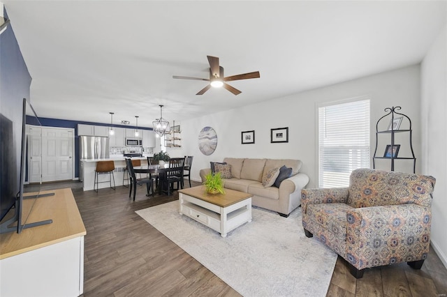 living room featuring dark wood finished floors and ceiling fan with notable chandelier
