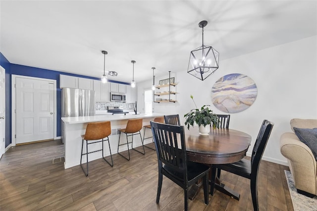 dining space featuring an inviting chandelier, baseboards, and dark wood-type flooring