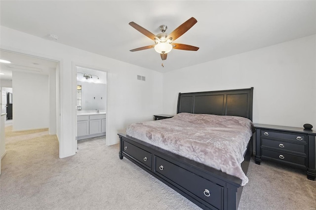 bedroom with baseboards, light carpet, a ceiling fan, and ensuite bath