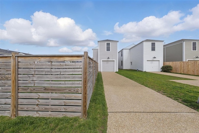 exterior space with a lawn, fence, driveway, and a garage
