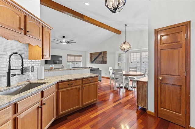 kitchen with a peninsula, a sink, a chandelier, tasteful backsplash, and dark wood-style floors