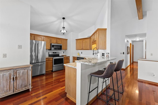 kitchen with stainless steel appliances, a peninsula, dark wood-type flooring, decorative backsplash, and a breakfast bar